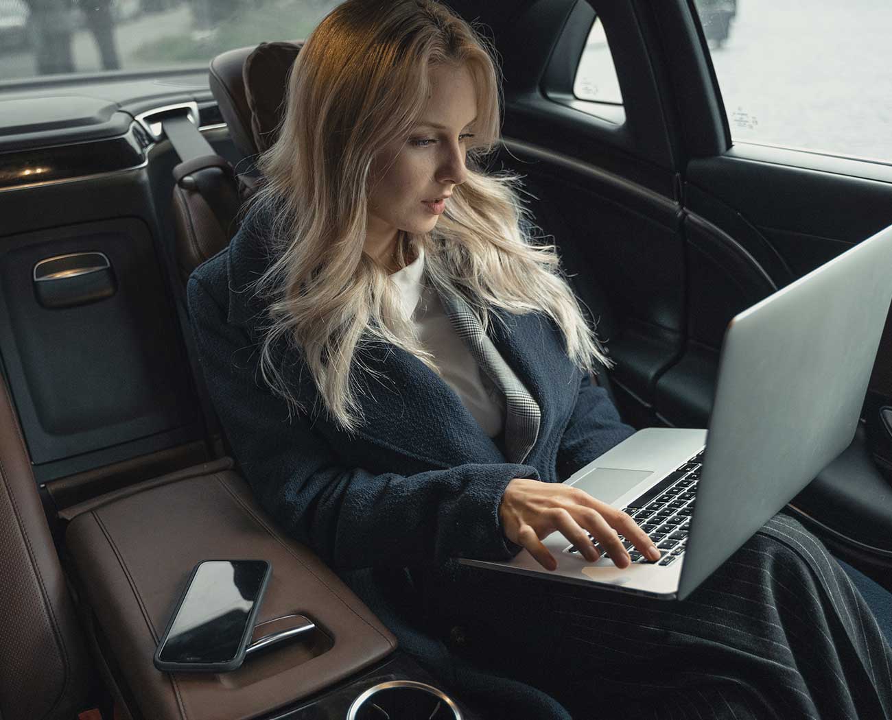 women in limousine working on her laptop